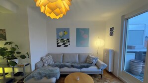 A modern living room with a sofa, a round coffee table, a hanging light fixture, and artwork on the walls.