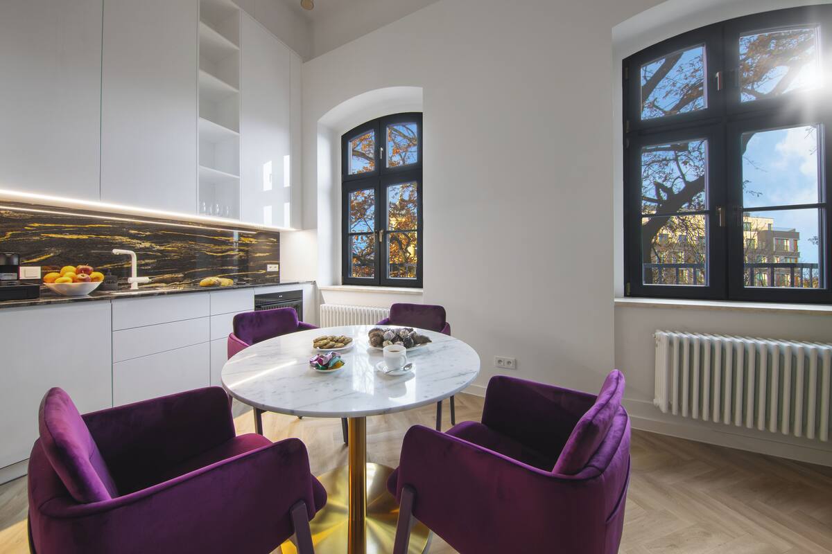 Une cuisine moderne avec un îlot en marbre, des chaises violettes et une table à manger.
