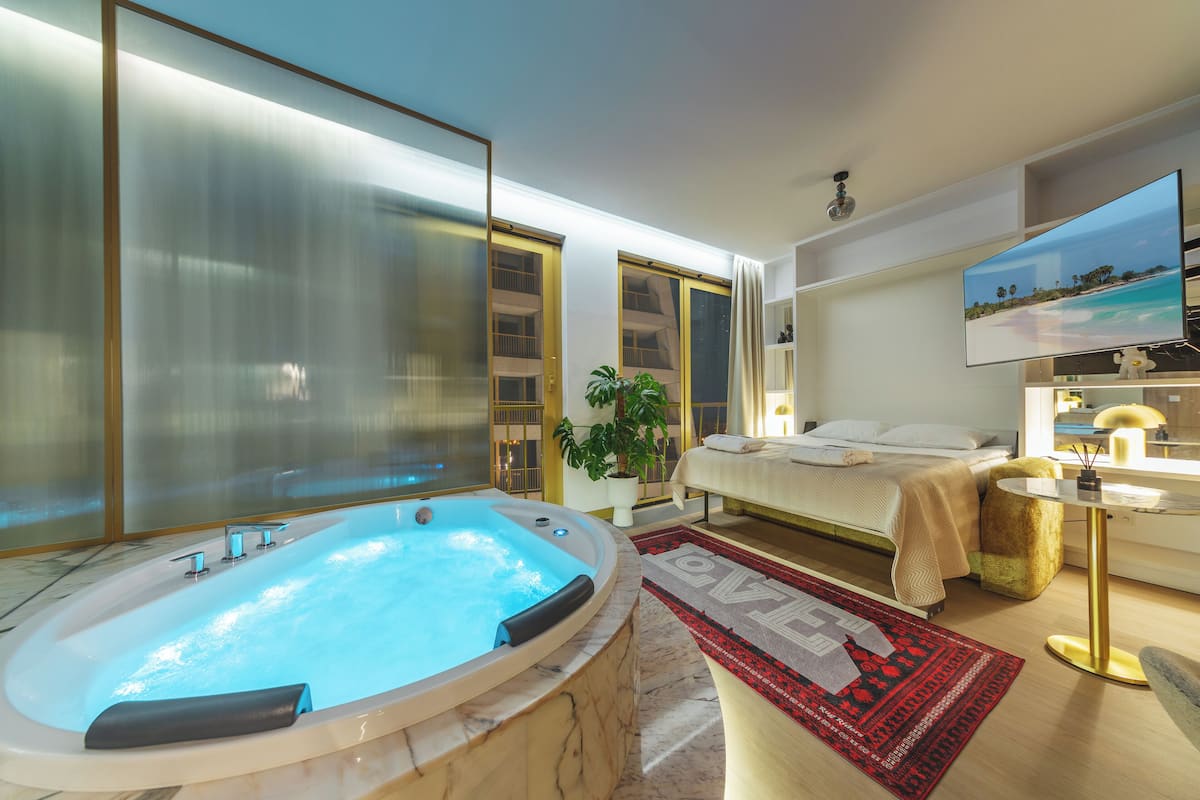 Une salle de bain moderne dotée d’une grande baignoire, d’un espace douche et d’un lit offrant une vue sur la plage.