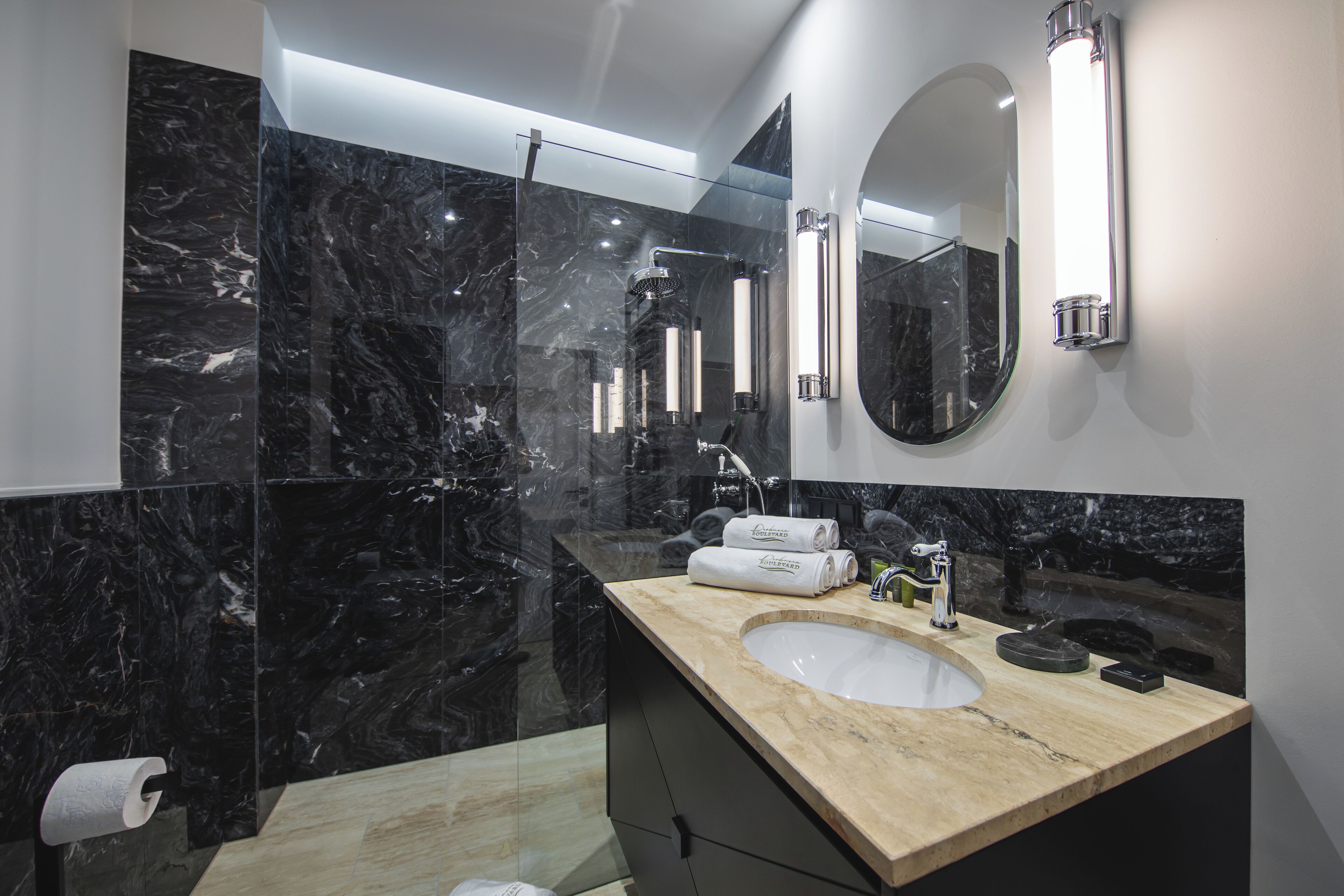 A modern bathroom with a marble sink, a large mirror, and a glass-enclosed shower.