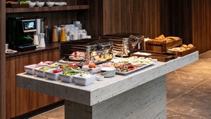 A buffet setup with various food items and a coffee machine. - Boulevard Drobnera Residence (Wroclaw)