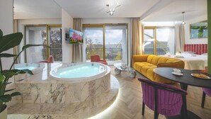 A modern living room with a marble jacuzzi, a yellow sofa, a dining table, and large windows offering a view of the outdoors. - Boulevard Drobnera Residence (Wroclaw)