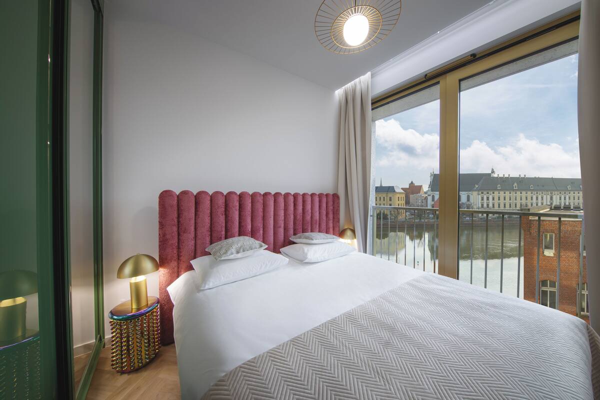 Une chambre d’hôtel avec un grand lit, une vue sur la ville et une lampe moderne.