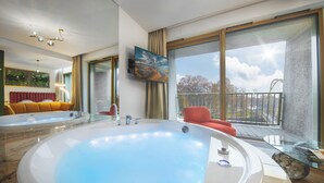 A modern bathroom with a large bathtub, a sofa, and a balcony with a view. - Boulevard Drobnera Residence (Wroclaw)