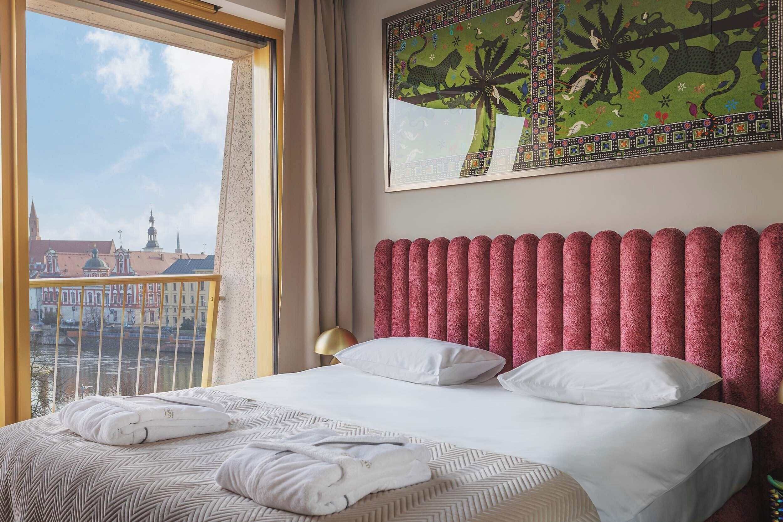 Une chambre d’hôtel avec un grand lit, une vue sur le paysage urbain et une tapisserie décorative au mur.