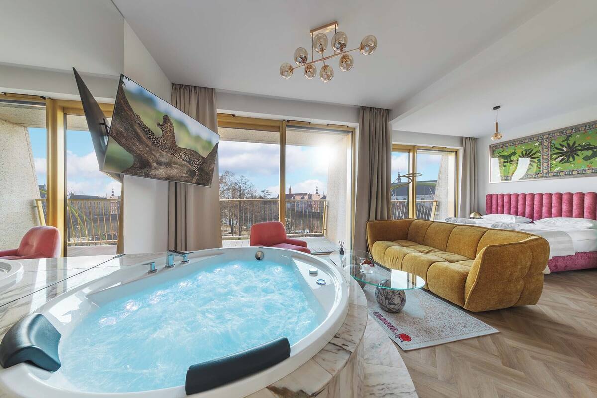 Un salon moderne doté d’un jacuzzi, d’un canapé et d’une grande fenêtre offrant une vue sur la ville.