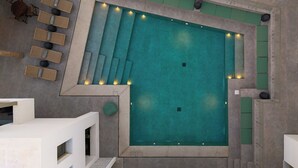 An indoor swimming pool with multiple seating areas and steps leading into the water. - Mazee Paros (Paros)