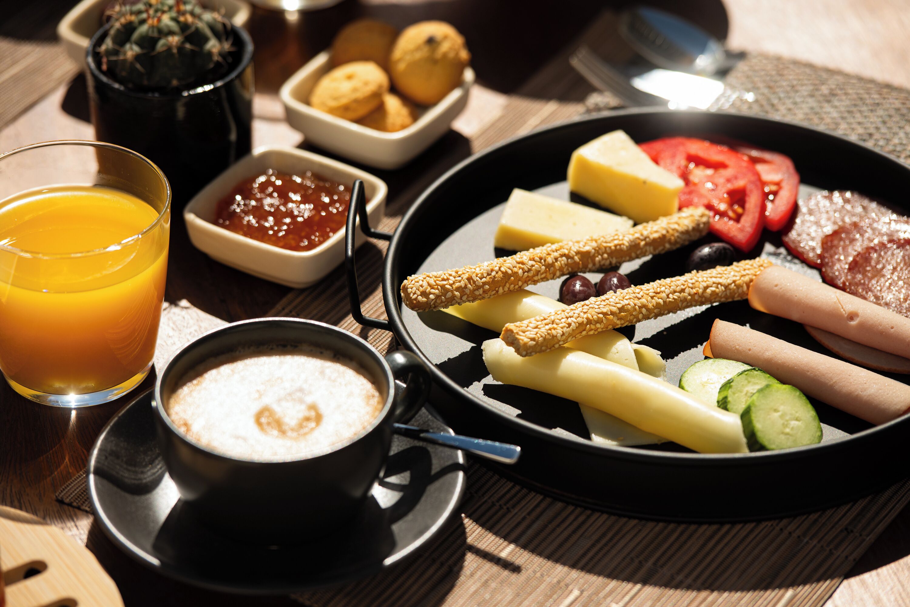 A breakfast tray with eggs, cheese, tomatoes, cucumbers, and breadsticks.