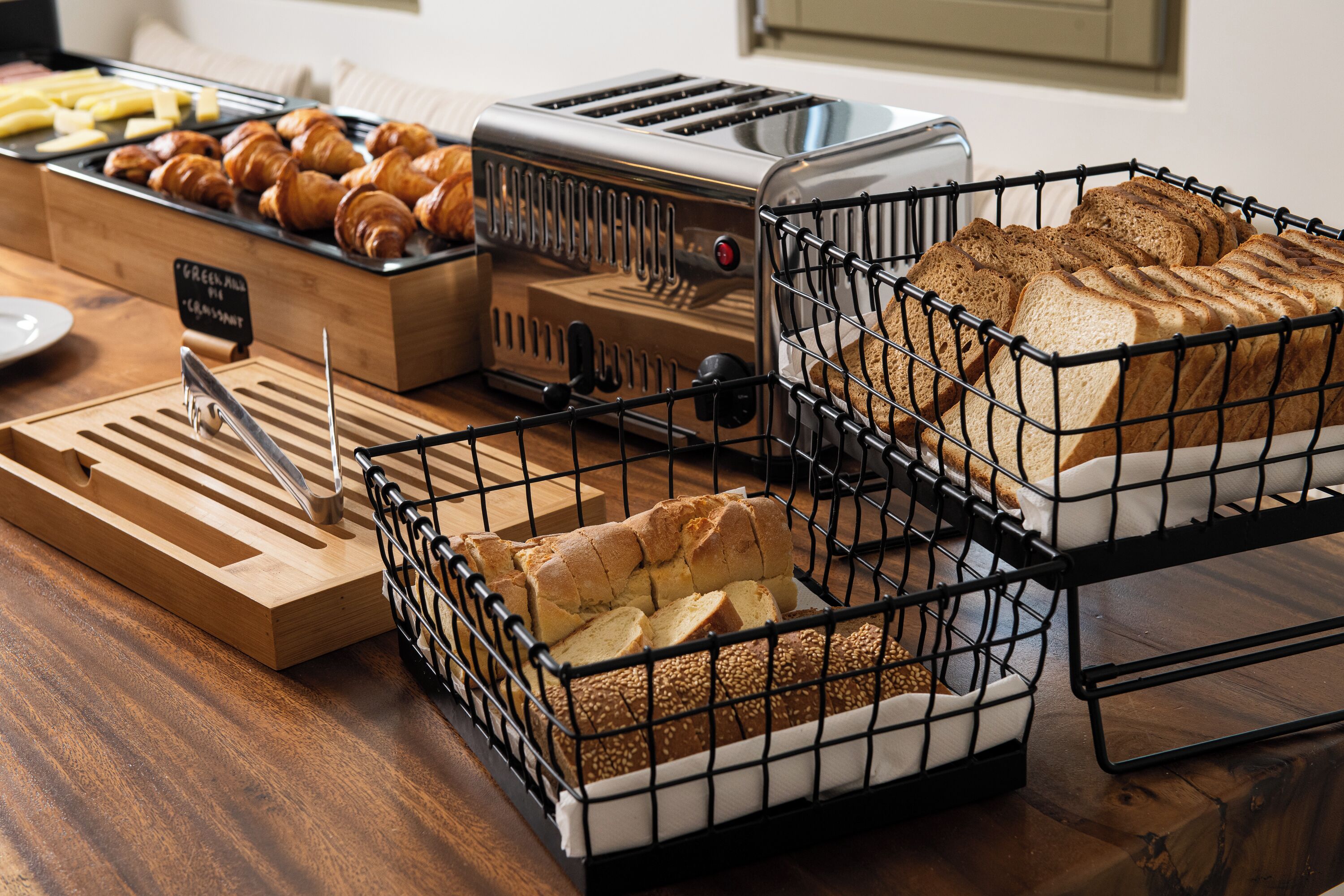 A breakfast buffet with croissants, bread, and a toaster.