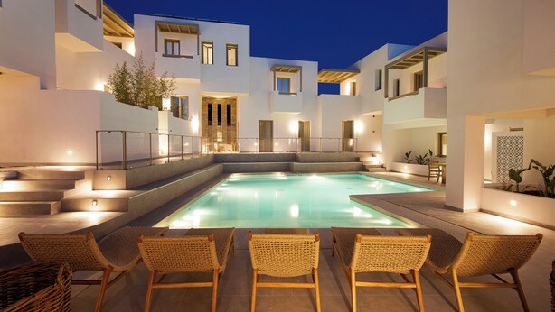 A modern pool area with a clear pool, surrounded by white buildings and wicker chairs. - Mazee Paros (Paros)