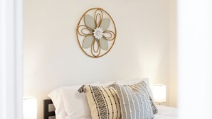 Ein ordentlich eingerichtetes Schlafzimmer mit Bett, Nachttischlampen, Wanddeko und Deckenventilator.
