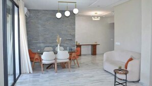 Un salon moderne comprenant un coin repas, un canapé et un lustre.