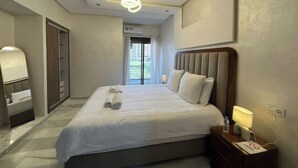 Une chambre d’hôtel moderne, dotée d’un grand lit, d’une table de chevet avec une lampe, d’une armoire et d’un luminaire au plafond.