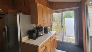 Eine kleine Küche mit Holzschränken, einem Edelstahlkühlschrank und einer Arbeitsplatte mit Kaffeemaschine und Mikrowelle.
