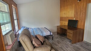 Ein gemütlicher Raum mit einem Bett, einem Liegesessel, einem Holztisch und einem Fernseher.