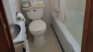 Ein kleines Badezimmer mit Toilette, Waschbecken und Badewanne.