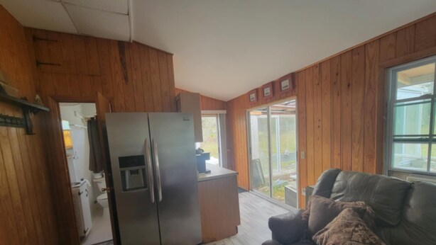 Eine Küche mit einem Edelstahl-Kühlschrank, einem Holfach und einer Schiebetür zu einer Terrasse.