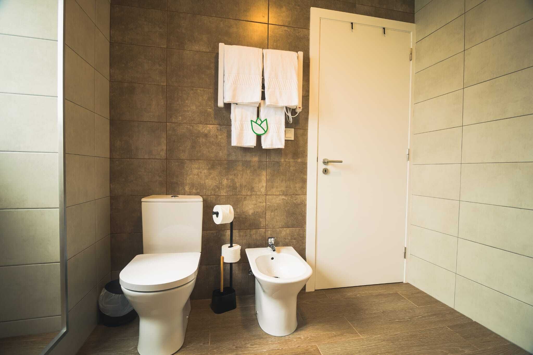 Une salle de bain moderne équipée de toilettes, d’un bidet et d’un porte-serviettes avec deux serviettes.