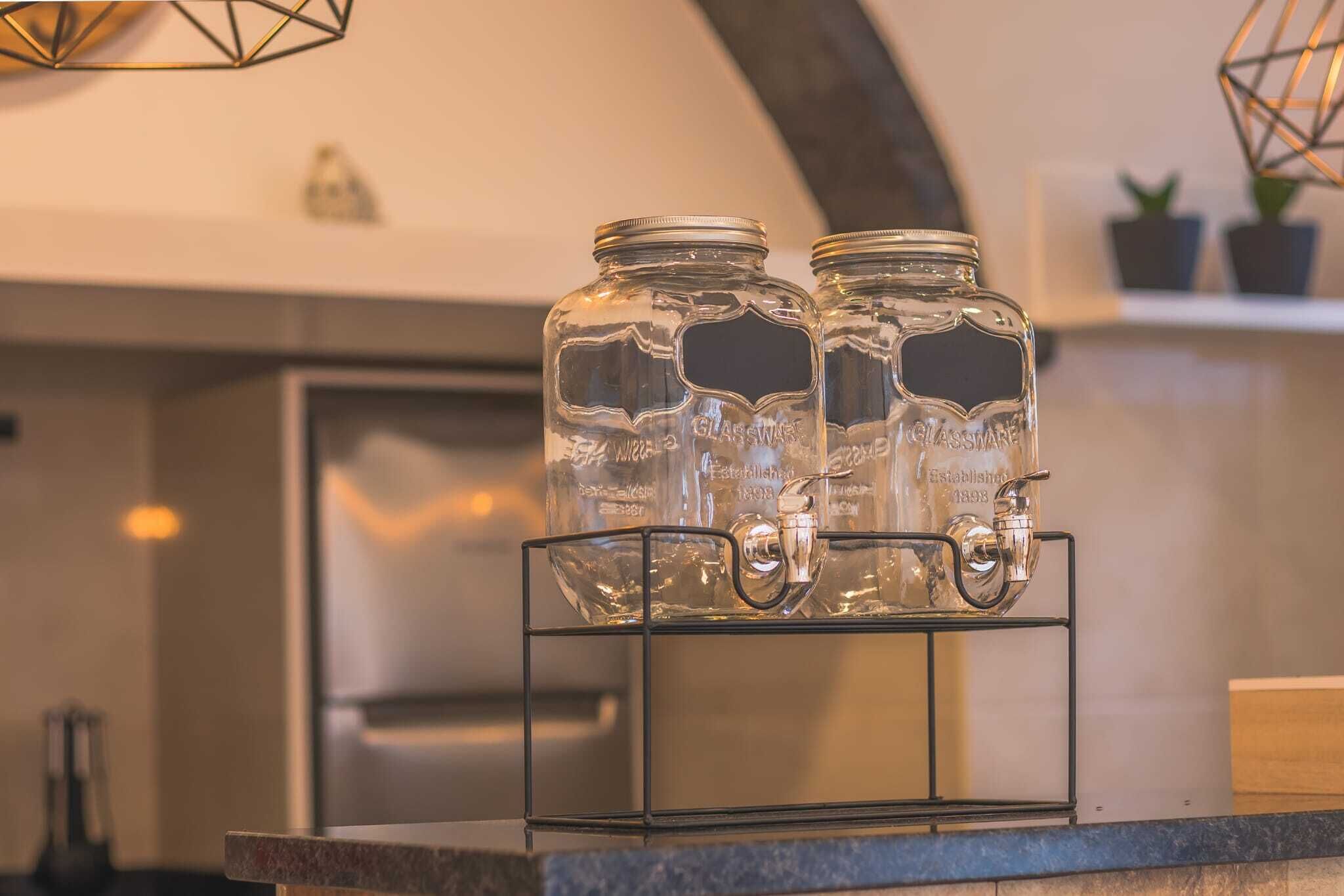 Deux bocaux en verre, dotés de couvercles en métal, posés sur un support métallique.