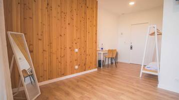 A room with a wooden panel wall, a white door, a small table with a chair, and a white shelf unit.