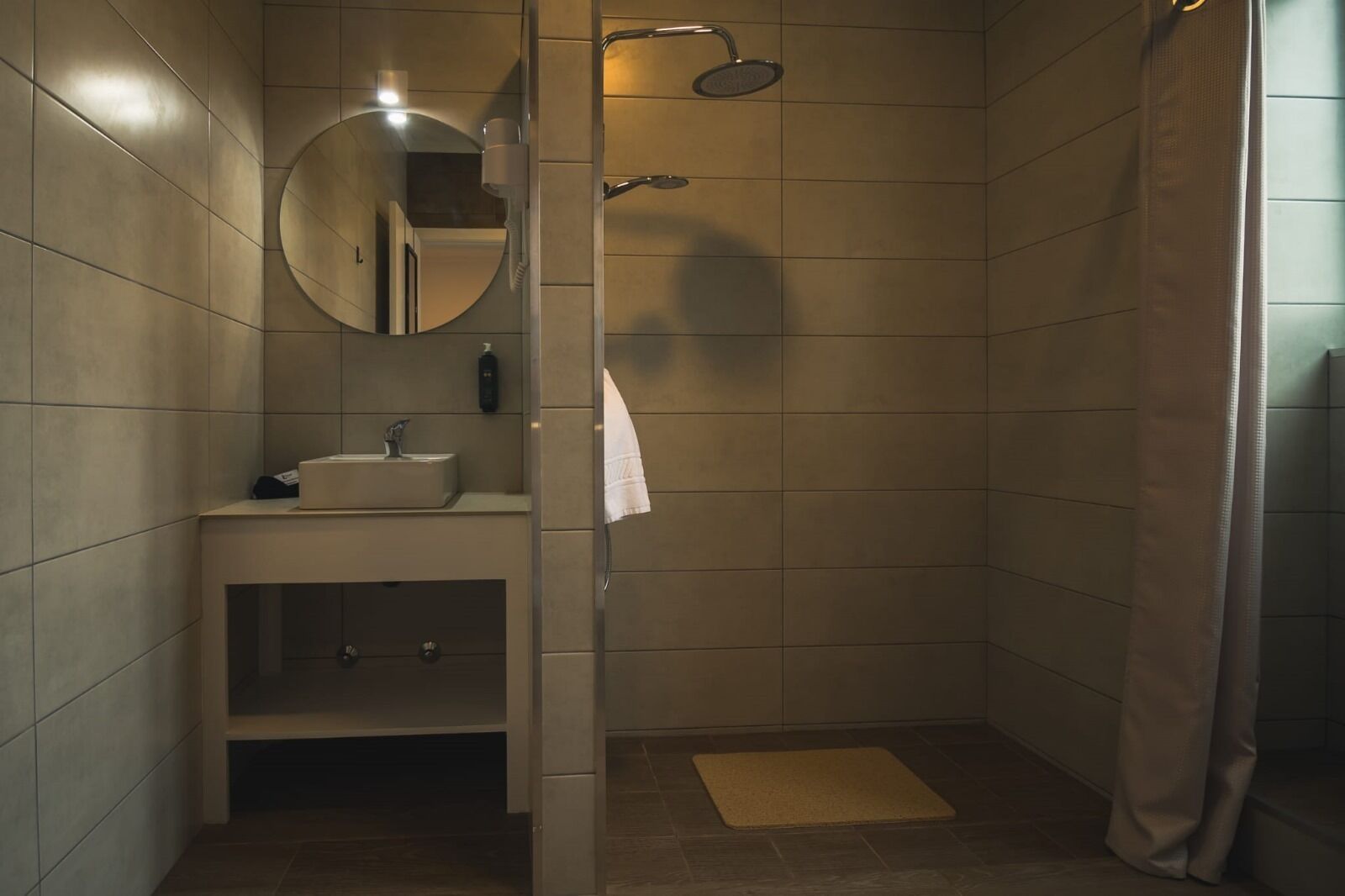 Un baño con ducha, lavamanos, espejo y toallero.