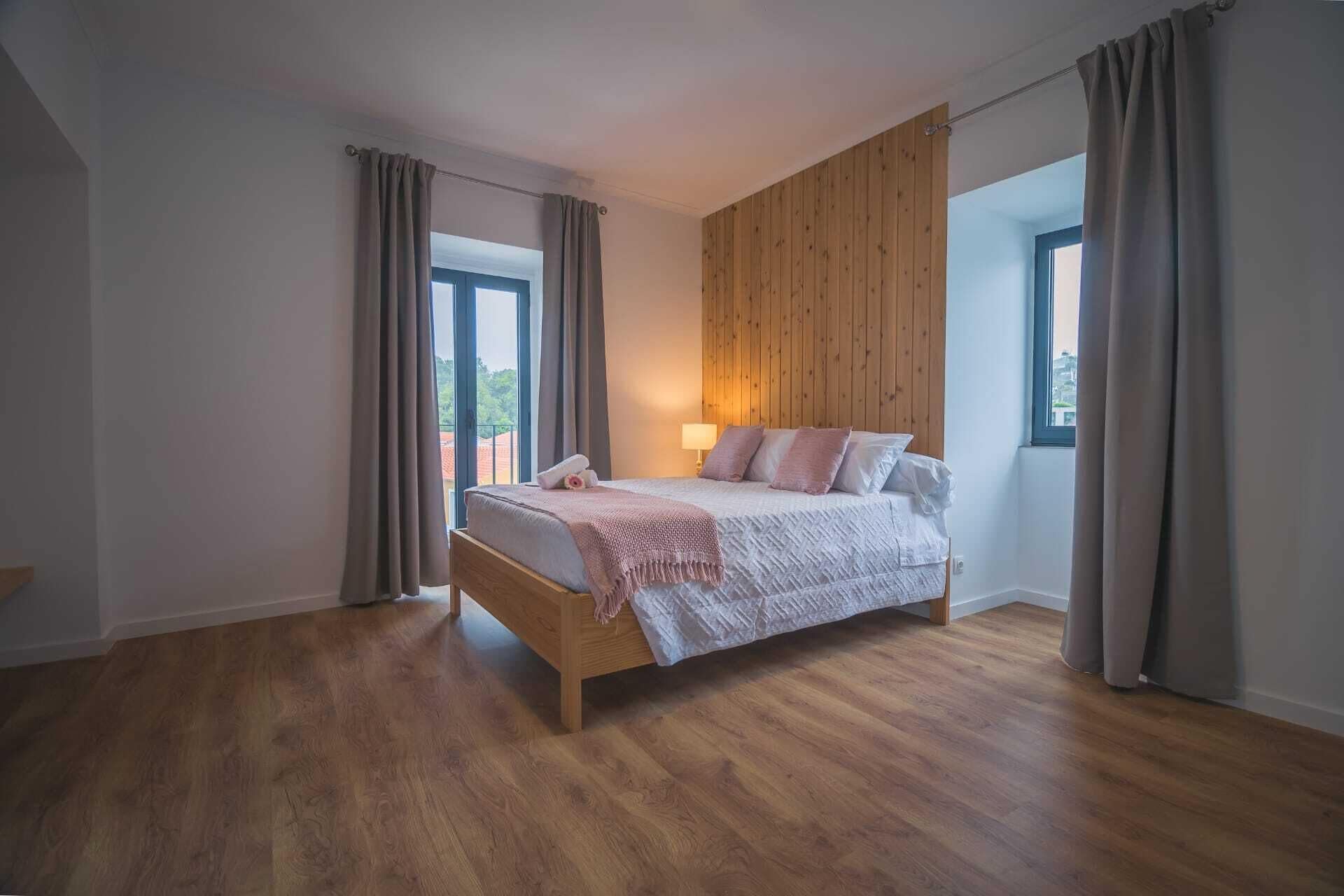 Una camera da letto con un letto in legno, vista sull'esterno e una parete rivestita in legno.
