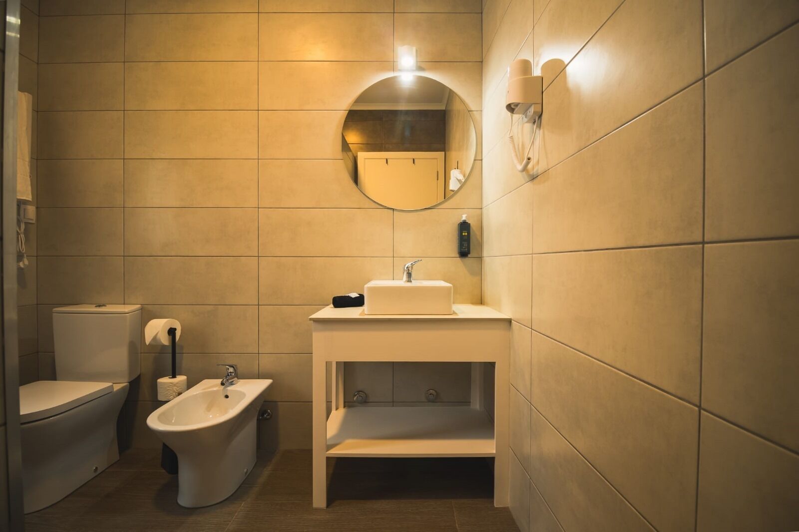 Ein modernes Badezimmer mit Toilette, Bidet, Waschbecken und Spiegel.