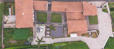An aerial view of a residential area with multiple houses, a parking lot, and a small green space.