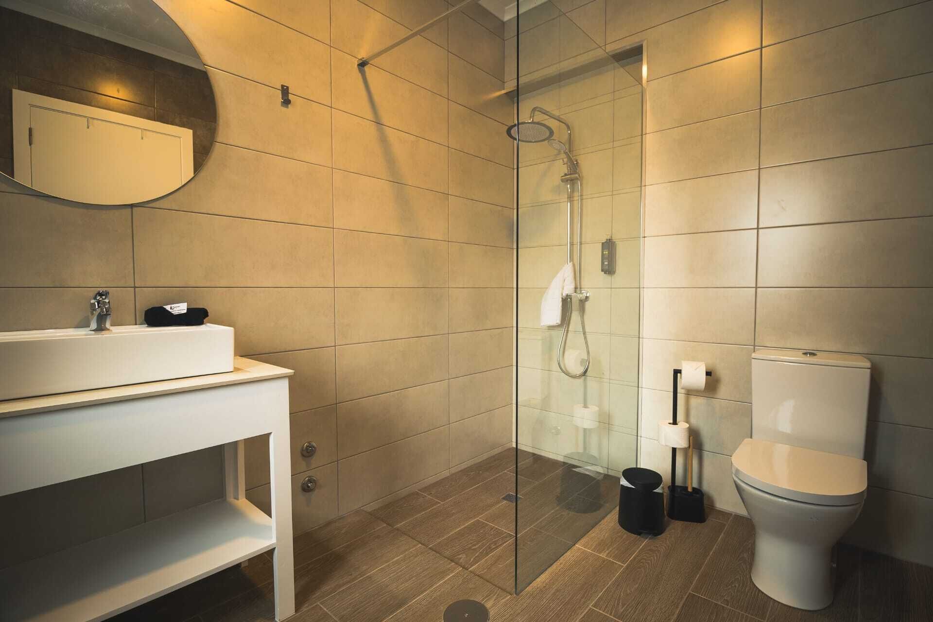 A modern bathroom with a glass-enclosed shower, a white sink, and a toilet.