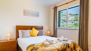 Une chambre d’hôtel avec un grand lit, une vue sur la ville et un tableau accroché au mur.