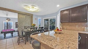 A spacious kitchen with dark wood cabinets, a granite countertop, and a dining area with a pool table. - Big Bass Hideaway with Hot Tub (Clifton Township)