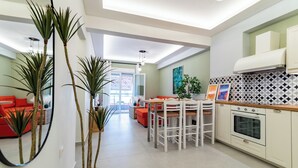 Une cuisine moderne avec des meubles blancs, un four encastré et un coin repas avec des chaises blanches.