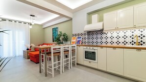 Une cuisine moderne avec des meubles blancs, un pare-feu en carrelage et un coin repas comprenant un canapé rouge et des chaises en bois.