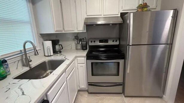 A kitchen with white cabinets, a stainless steel refrigerator, a stove, and a sink. - Spacious Charming 3-bedroom house with WiFi and AC in Burlington (Burlington)