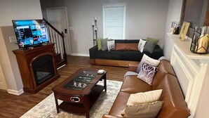 A living room with a fireplace, a television, a sofa, and a coffee table. - Spacious Charming 3-bedroom house with WiFi and AC in Burlington (Burlington)