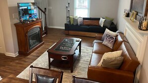 A living room with a fireplace, a sofa, a coffee table, and a television. - Spacious Charming 3-bedroom house with WiFi and AC in Burlington (Burlington)