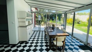 Une véranda avec un sol à carreaux, une table à manger et des chaises.