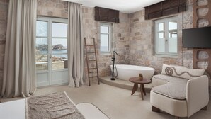 Une salle de bain avec une baignoire, un ventilateur de plafond et une vue sur la mer.