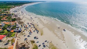 An aerial view of a beach with numerous beachgoers and parked vehicles. - Salinas Exclusive Resort (Salinópolis)