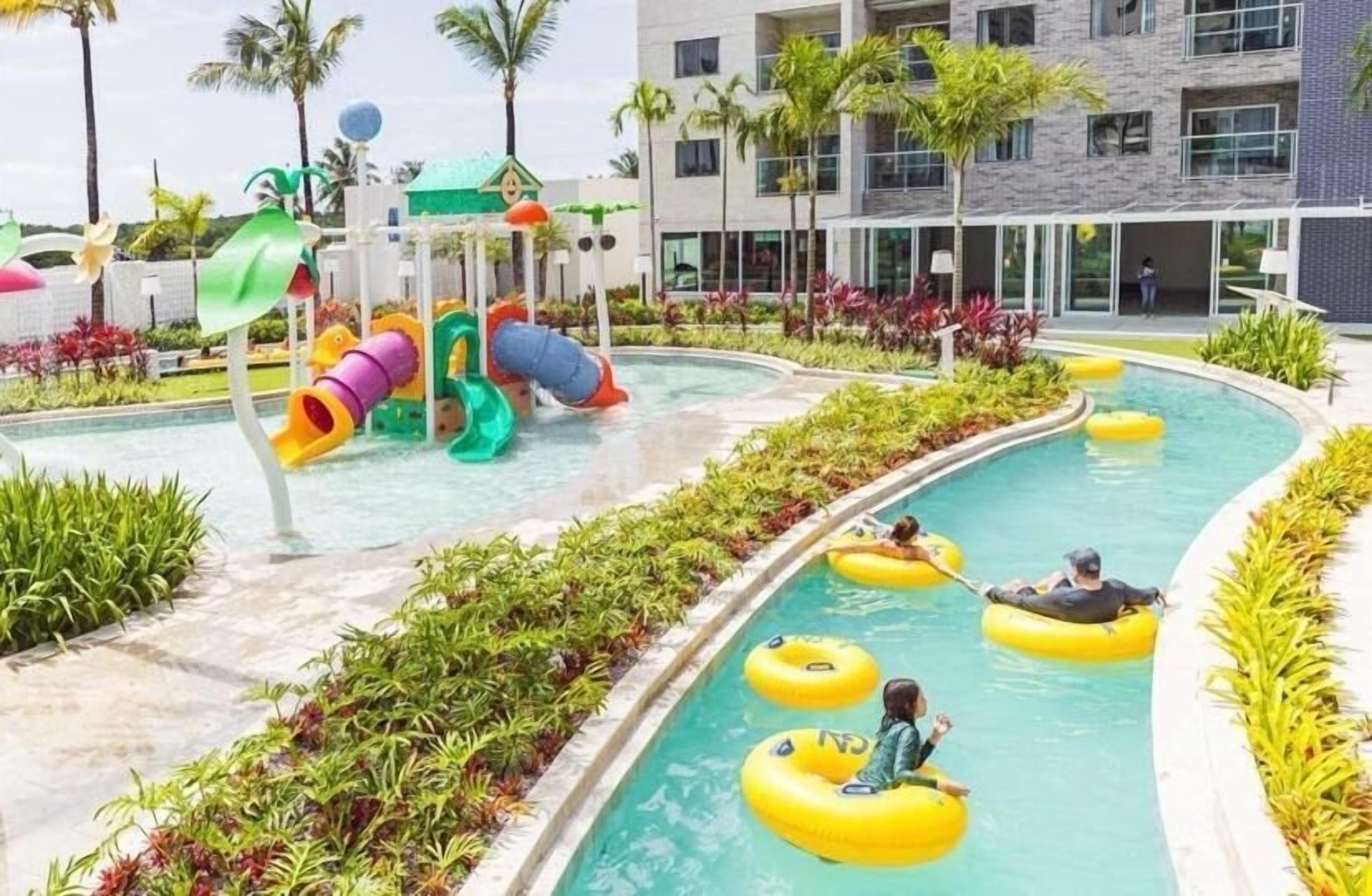 A pool area with water slides and inflatable rings.
