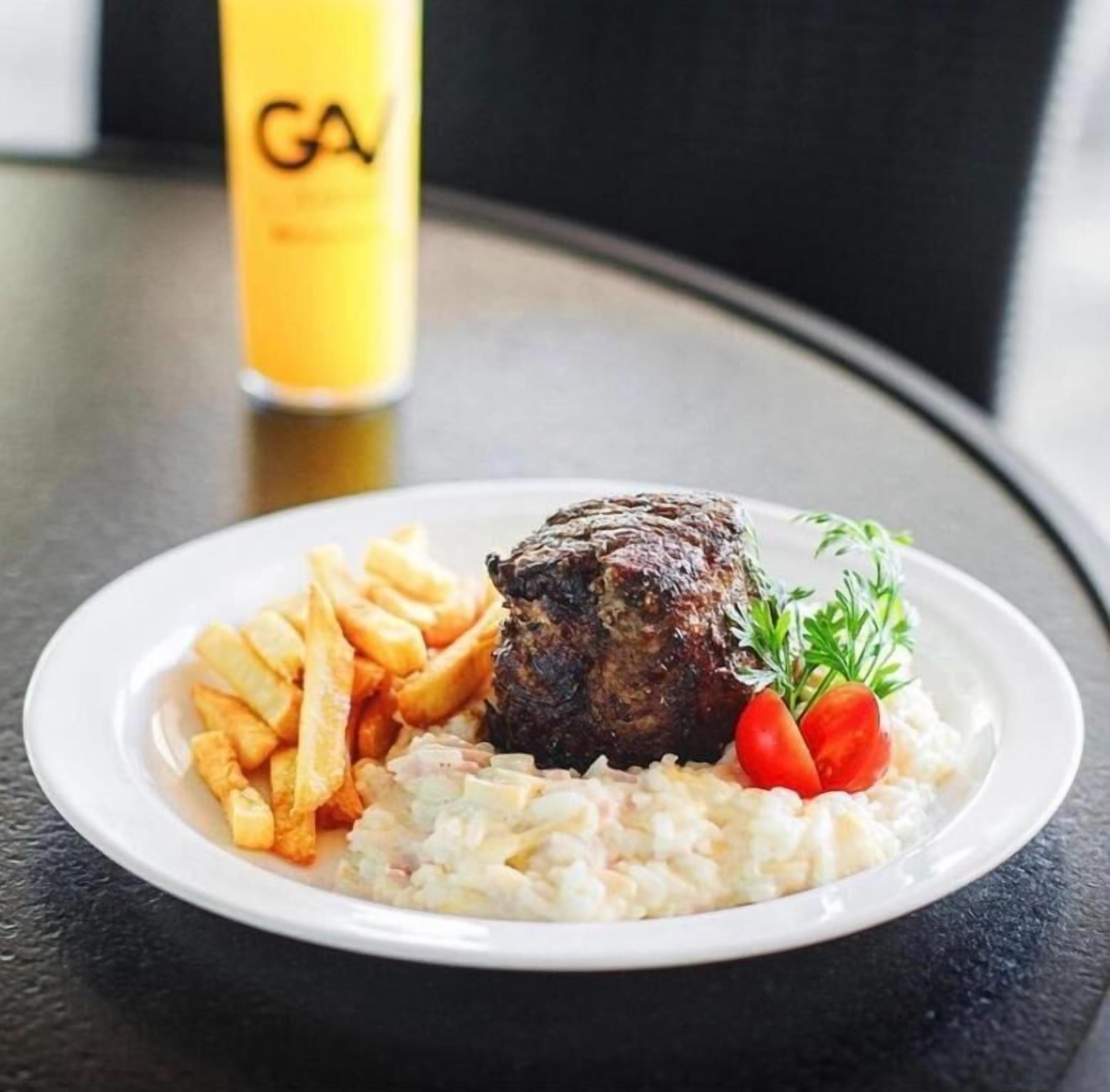 A plate with a steak, fries, and a salad on a table.