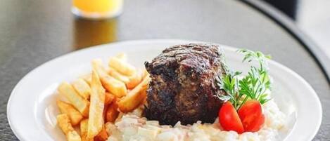 A plate with a steak, fries, and a salad on a table.