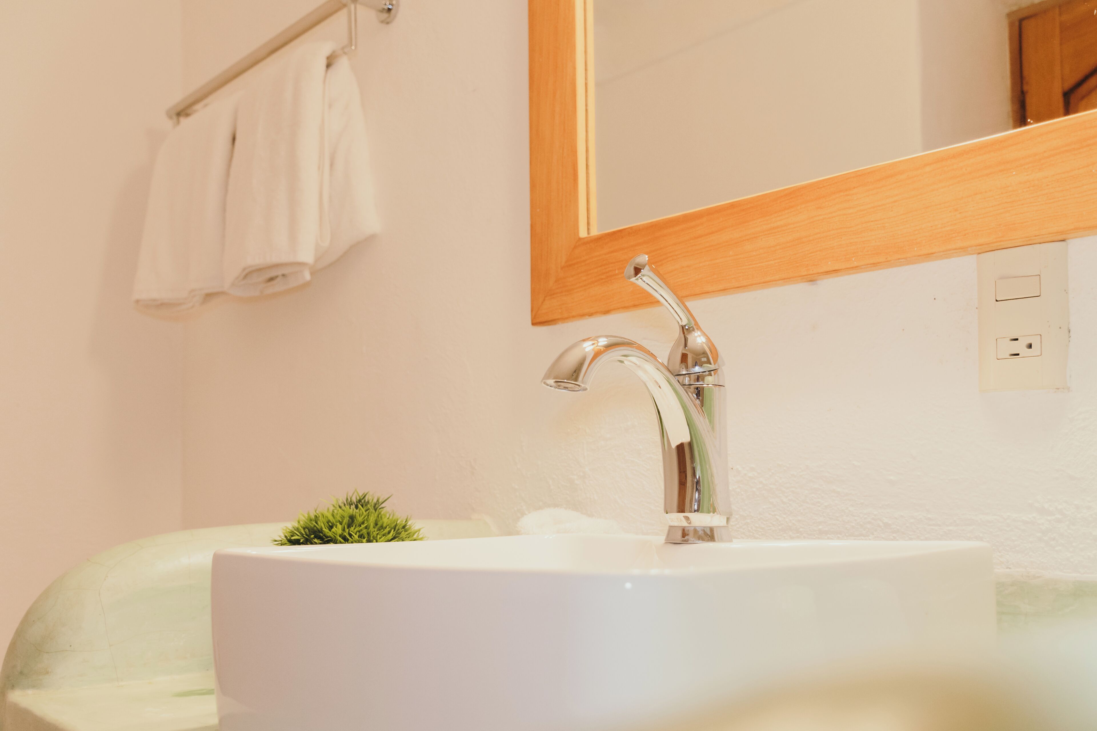 A bathroom with a white sink, a mirror, and a towel rack.