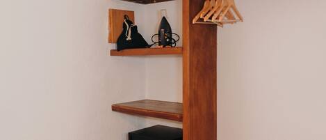 Un armario de madera con estantes, una barra para colgar ropa y una pequeña caja fuerte.