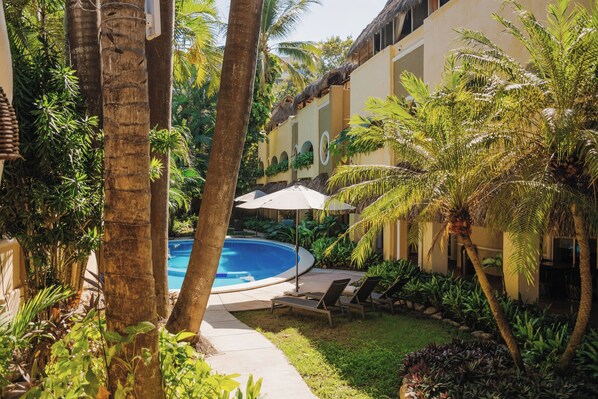 A pool area with lounge chairs and umbrellas, surrounded by palm trees and tropical plants. - Casa Real Sayulita Hotel Boutique (Sayulita)