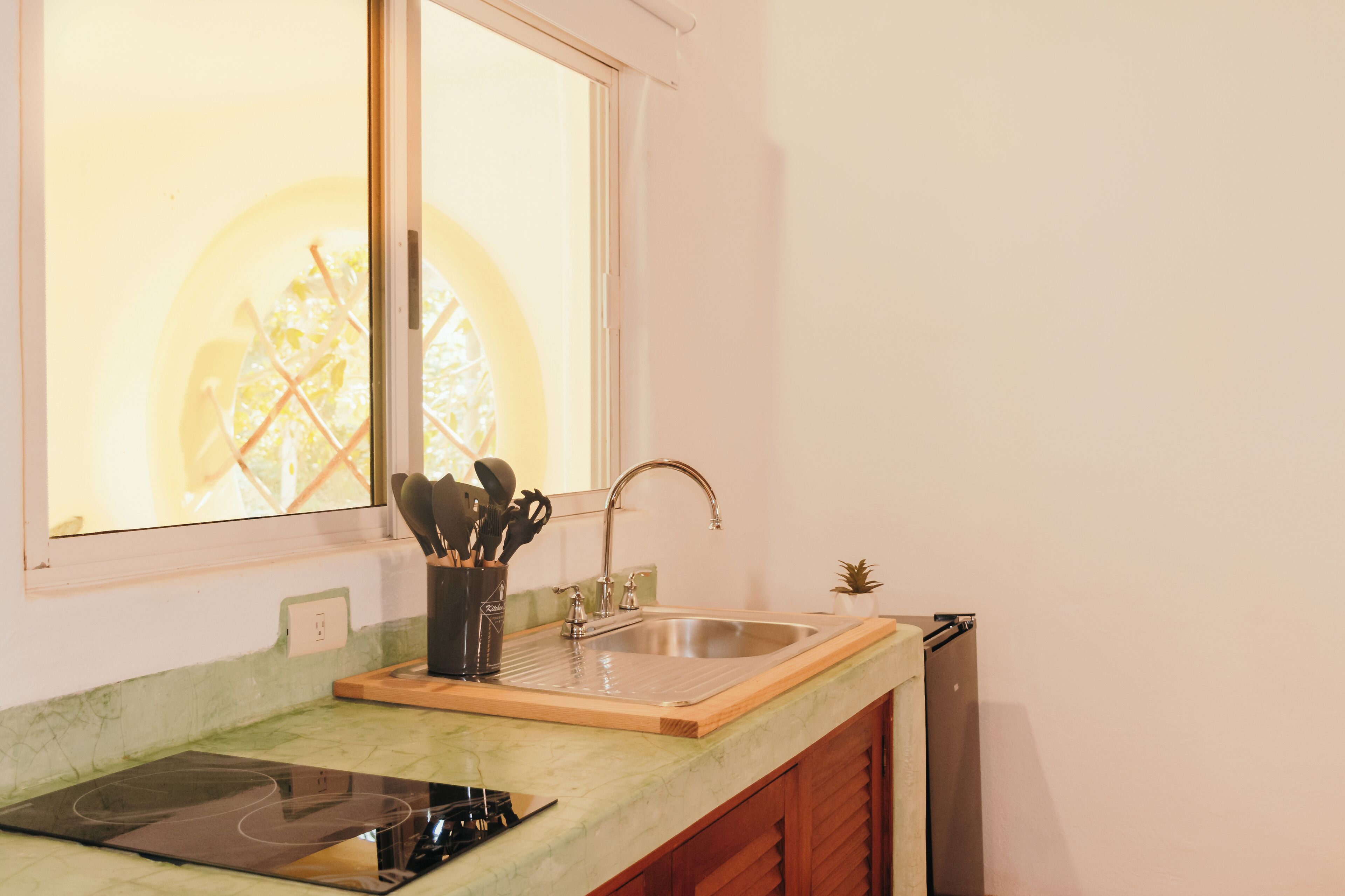 A kitchen with a built-in stove, a sink, and a window above the sink.