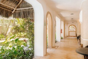 A corridor with arches, a thatched roof, and potted plants. - Casa Real Sayulita Hotel Boutique (Sayulita)