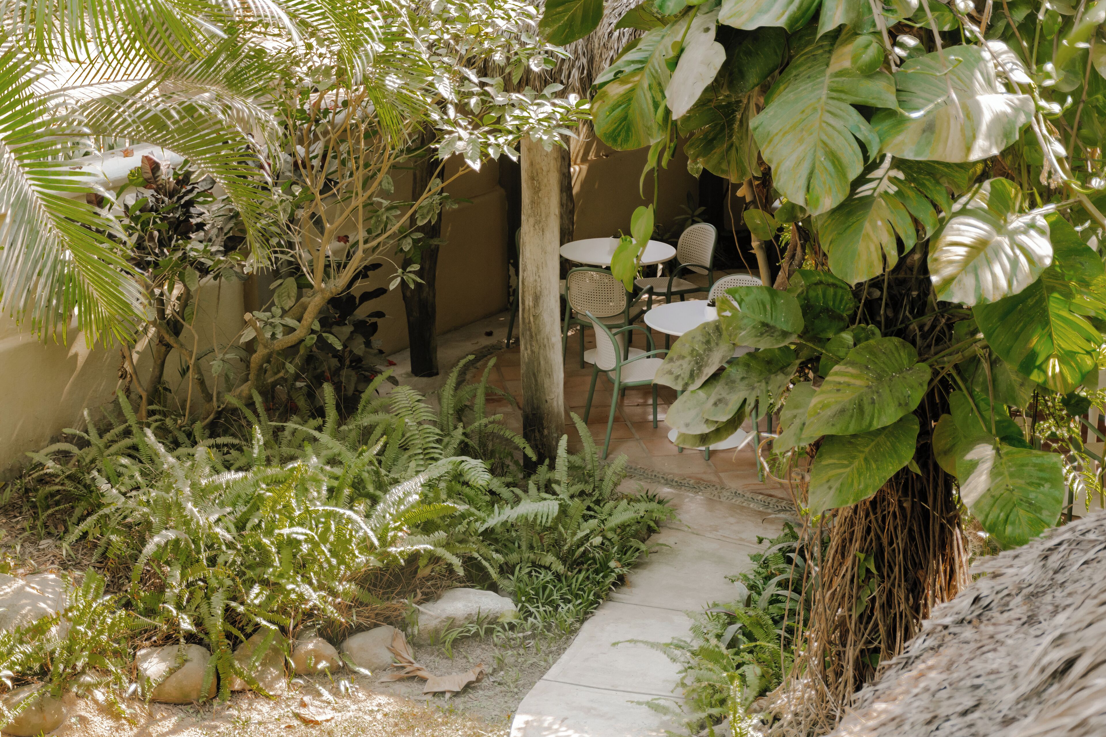 A garden area with a pathway leading to a seating area with tables and chairs.