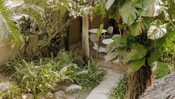 Un jardín con un sendero que lleva a una zona de estar, con mesas y sillas.