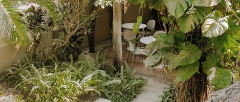 Un espace jardin agrémenté d’un sentier menant à un coin salon avec des tables et des chaises.